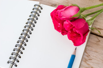 Red rose flower and vintage book on the wooden, valentine's day