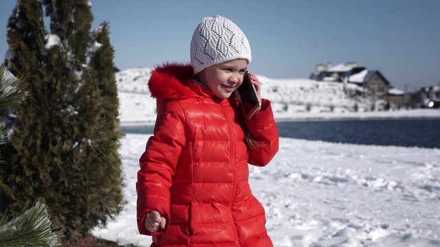 Little girl in a red jacket talking on the phone