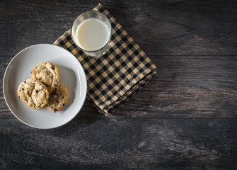Chocolate chip cookies and milk served on a wood table