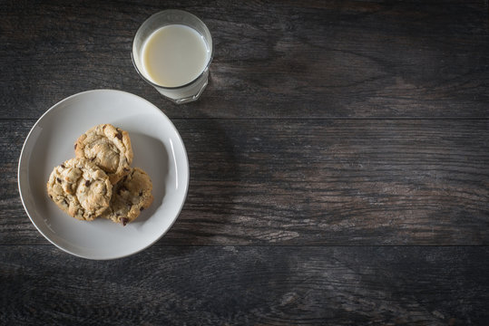 Chocolate chip cookies and milk served on a wood table