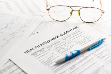 Health insurance claim form with glasses and ballpoint pen.