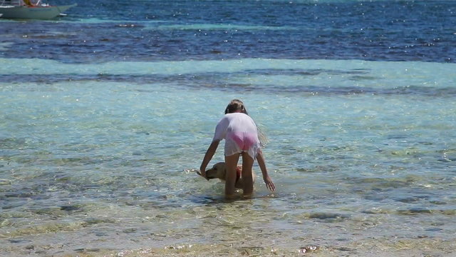 Young girl and dog playing in the water, the sea on a tropical beach.Happy girl playing with her dog in water.Travel concept.Family,summer vacation.