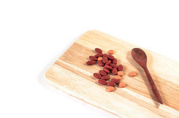 Pill spilling on log with old wooden spoon in white background