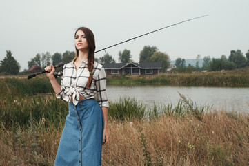  country lady standing against pond on ranch with fish-rod 