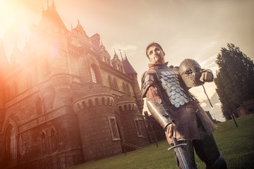 Medieval knight with the sword on the ancient castle background