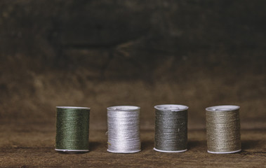 Set of Four Green and Khaki Sewing Spools on Wood Background