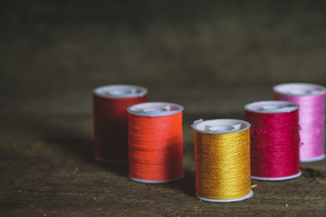 Set of Five Orange, Red and Pink Sewing Spools on Wood Backgroun