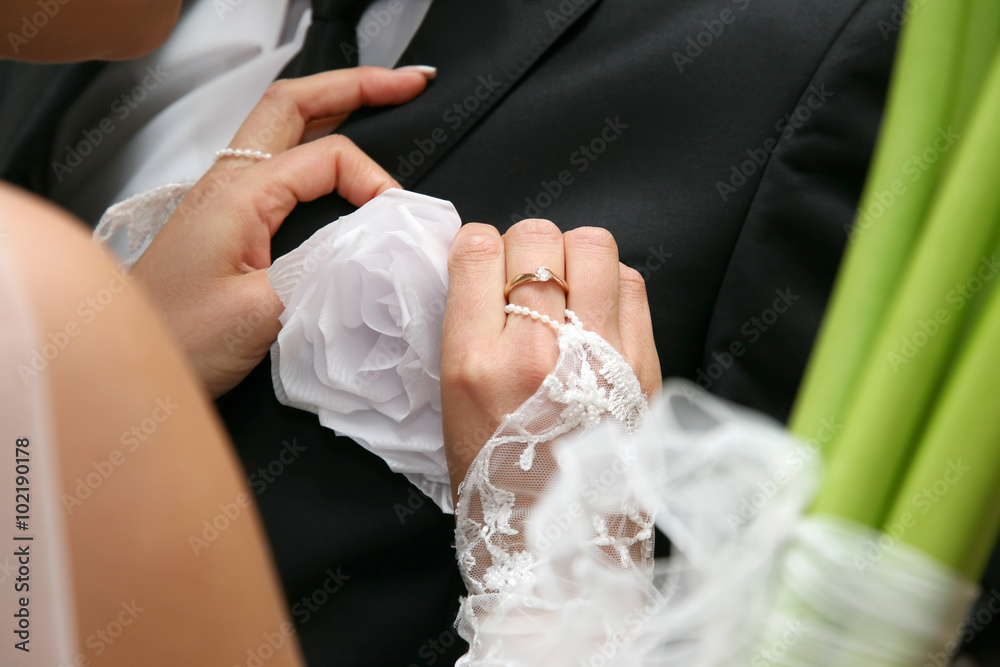 Wall mural bride helps the groom to wear a wedding flower on suit