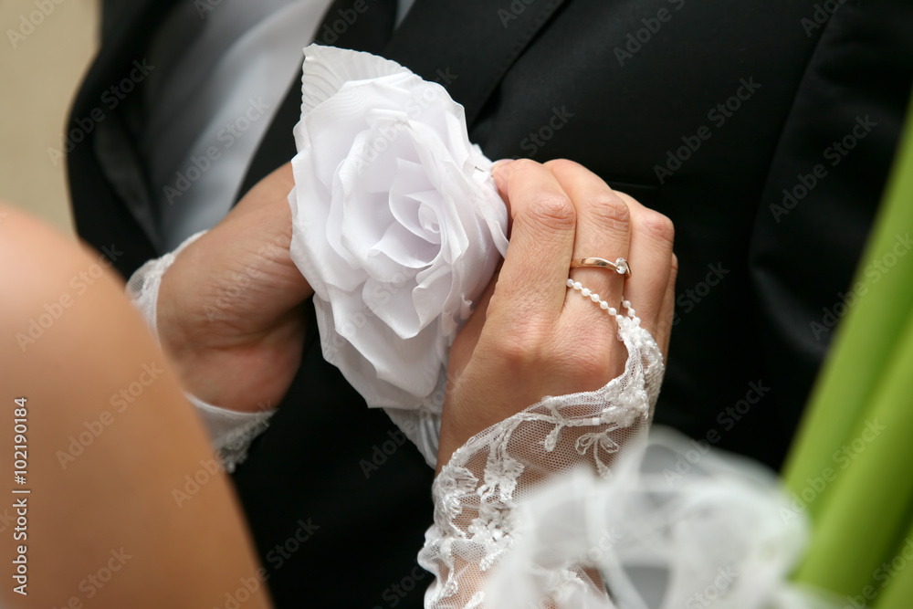 Wall mural bride helps the groom to wear a wedding flower on suit