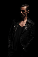 serious biker in leather jacket posing with hands in pockets