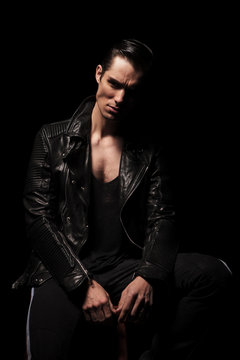 fashionable rocker in black leather jacket posing seated