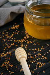 Buckwheat Honey in a glass jar and pollen on the wood table