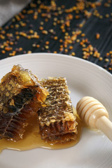 Fresh Honeycombs on plate, honey and pollen on background