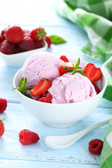 Ice cream in bowl with strawberries and raspberries on blue wood