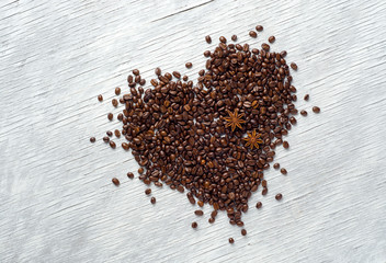 Heart shape made from coffee beans on wooden background