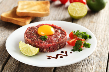 Beef tartare with egg yolk on a grey wooden table