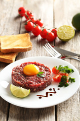 Beef tartare with egg yolk on a grey wooden table