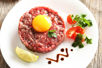 Beef tartare with egg yolk on a grey wooden table