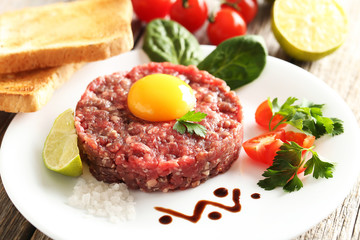 Beef tartare with egg yolk on a grey wooden table