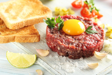 Beef tartare with egg yolk on a blue wooden table