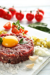 Beef tartare with egg yolk on a blue wooden table