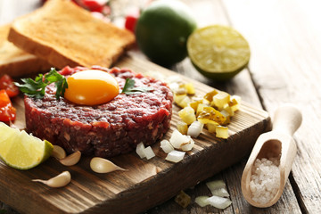 Beef tartare with egg yolk on a grey wooden table