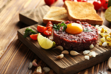 Beef tartare with egg yolk on a brown wooden table