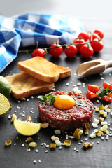 Beef tartare with egg yolk on a black wooden table