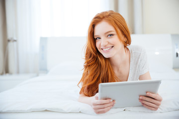 Woman lying on the bed with tablet computer