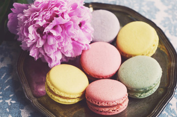 Pastel colored macaroons on a metal tray and peony flower