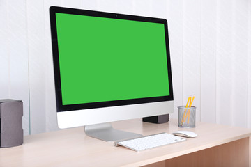 Modern computer with green screen, on table
