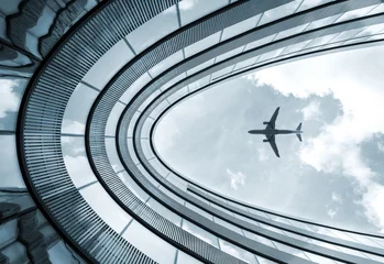 Modernes Architekturgebäude des niedrigen Winkels mit landendem Flugzeug © BOOCYS