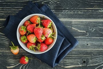 Organic strawberries in a white bowl on a rustic wooden table, T