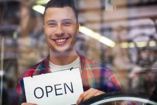 Bike Shop Owner Holding Open Sign
