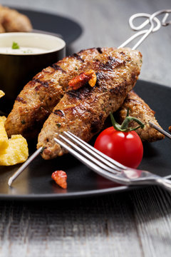 Barbecued kofta - kebeb with fries and vegetables on a plate.