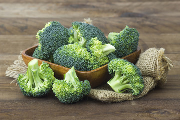 Raw broccoli in a bowl on wooden background