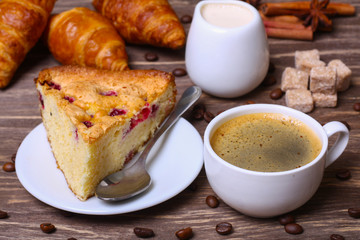 cup of coffee with cake with cranberries and croissants on a wooden background