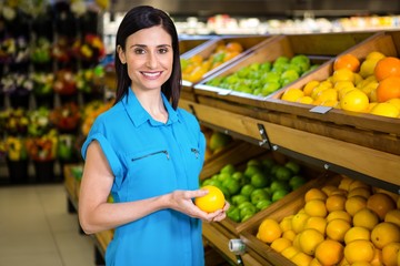 Portrait of a smiling woman picking orange