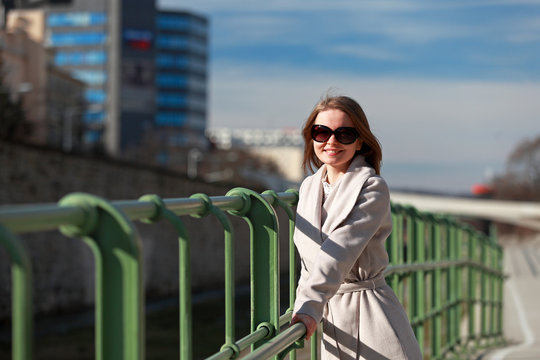 Beautiful blonde woman with coat and sunglasses leaning on a handrail