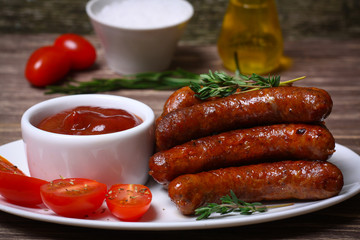 roasted sausages with tomato sauce and herbs on a wooden background