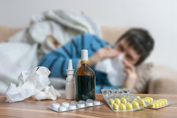 Pills in front of sick man who has flu or cold. - obrazy, fototapety, plakaty