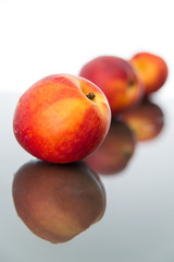 Peaches on glass sheet with backlight, vertical, front view.