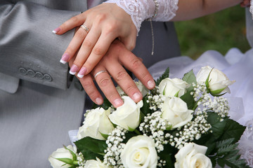 Obraz na płótnie Canvas hands of bride and groom near wedding bouquet