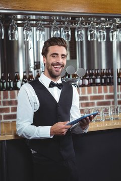 Handsome barman using tablet computer