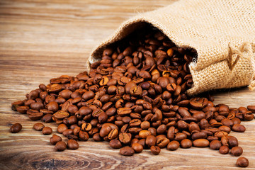 The sack of coffee beans on wooden background