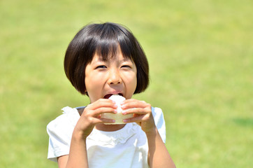 芝生広場でおにぎりを食べる女の子