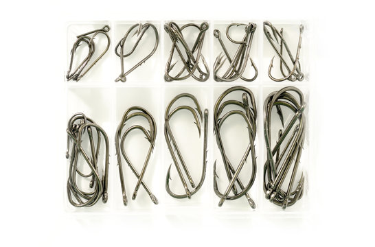 Different sizes of fishing hooks in plastic box isolated on whit