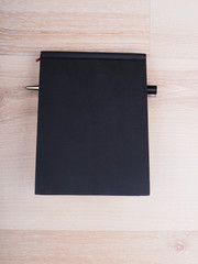 black notebook with a pen on a wooden background