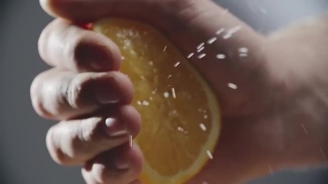 Close up of male hand squeezing fresh orange juice