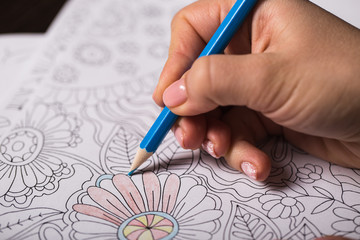 Girl paints a coloring book for adults with crayons - 102217788